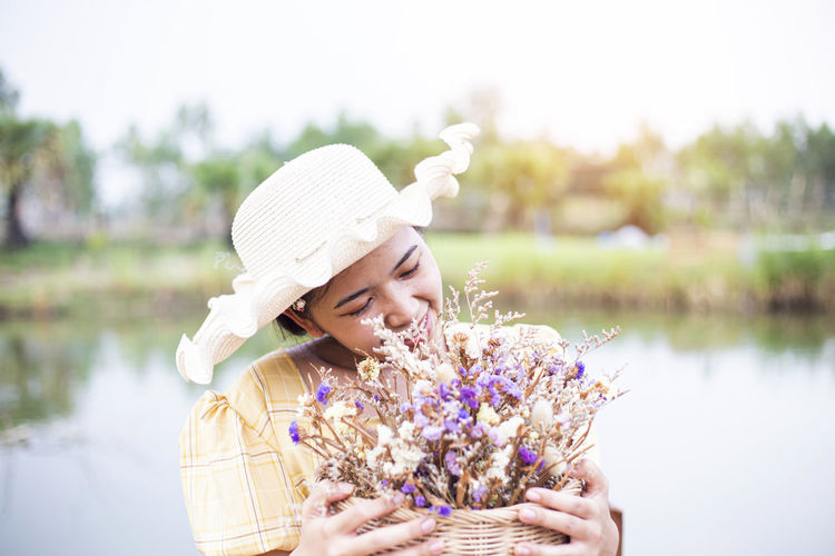 Portrait of woman with pink flowers against lake