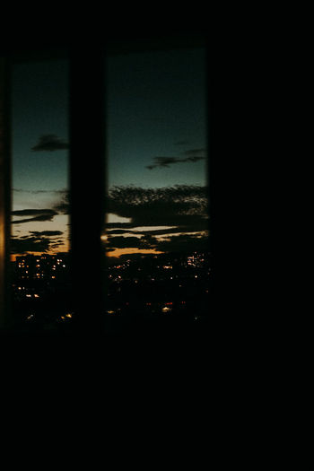 Silhouette city seen through glass window at night