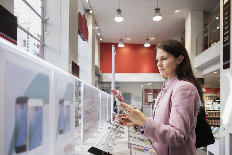 Side view of woman using smart phone in store