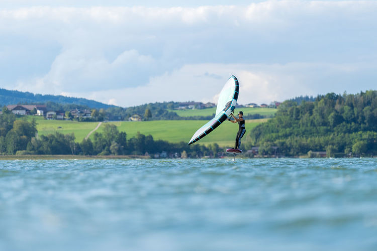 Woman wing foiling on lake wallersee, salzburg, austria.