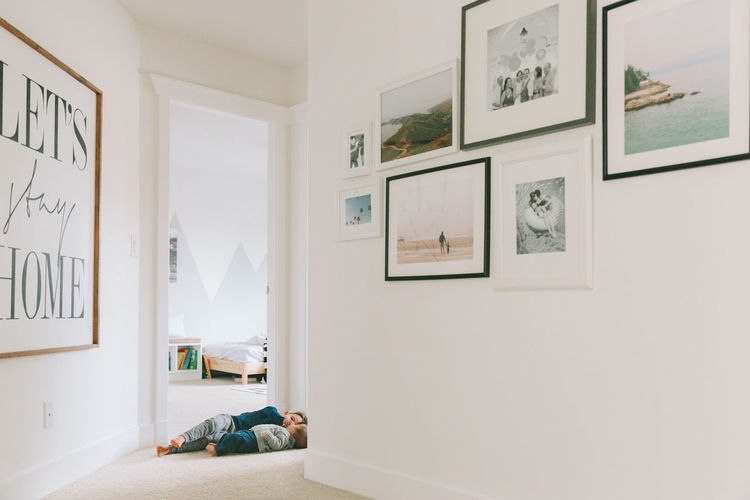 Siblings lying in corridor at home