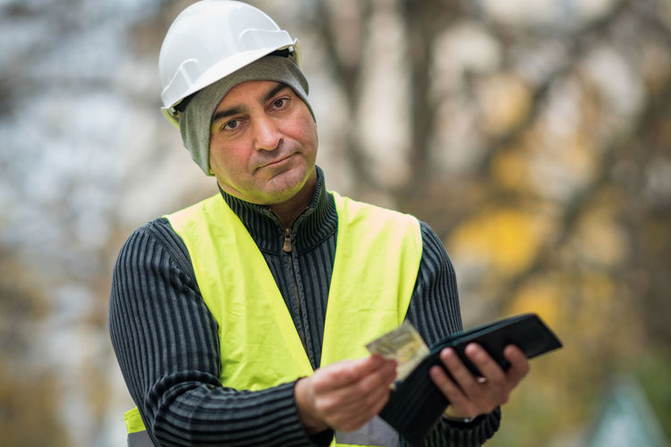 Portrait of engineer in reflective clothing holding wallet
