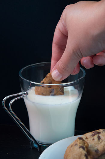 Cropped hand having cookies with milk