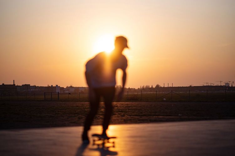 Silhouette man skateboarding against sky during sunset