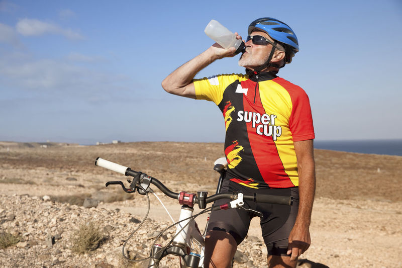 Spain, canary islands, fuerteventura, senior man with mountainbike drinking from bottle