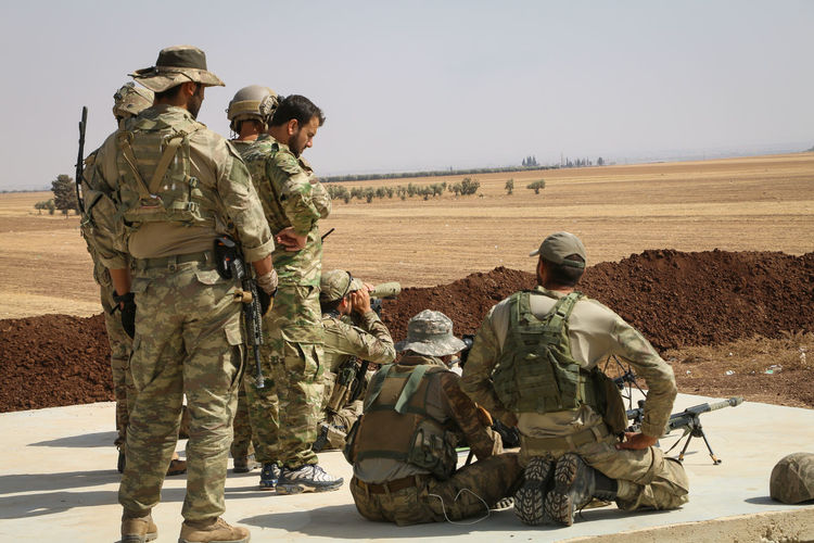 Rear view of soldiers in desert against sky