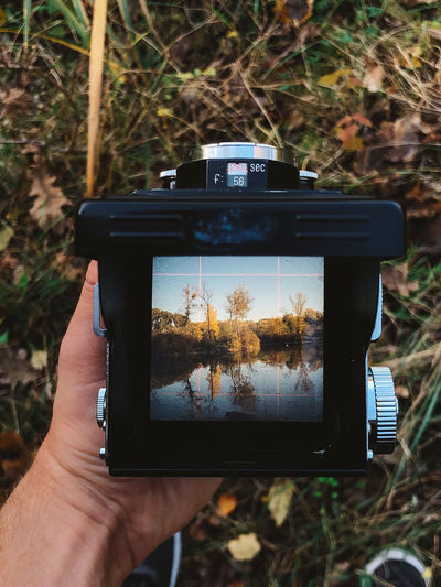 Looking through a vintage medium format camera's viewfinder towards a calm lake in the fall.