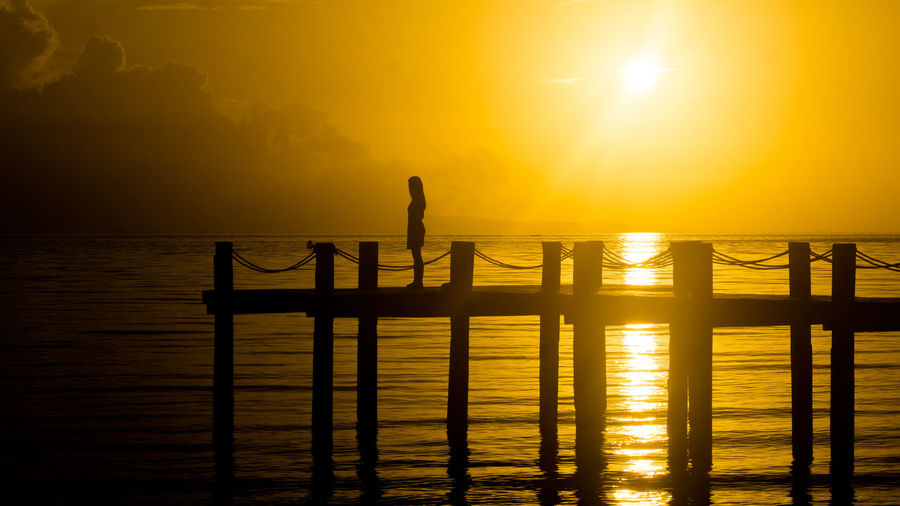 Silhouette of woman standing on pier