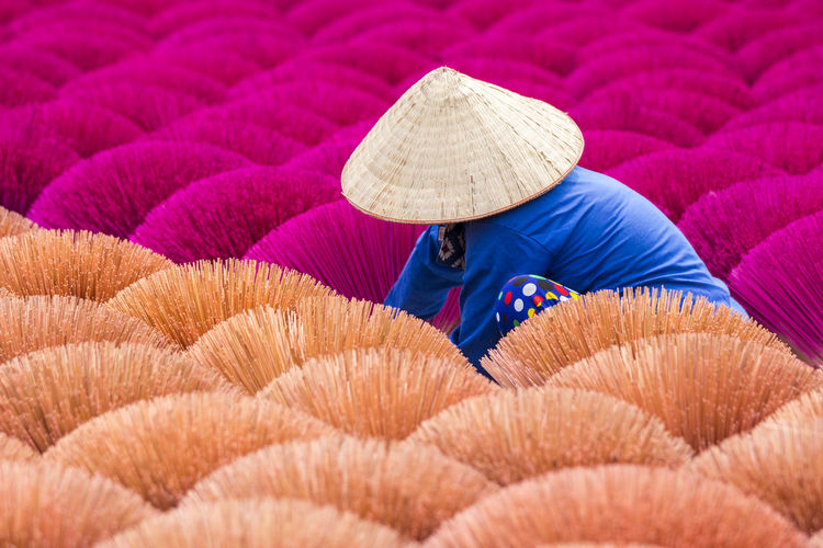 Vietnamese worker surrounded by vibrant bouquets of incense sticks.  cultures around the world.