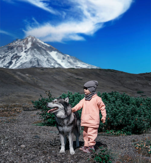 Girl with dog on mountain against sky