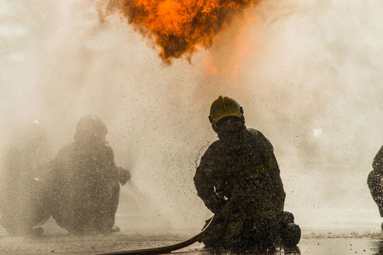 Rear view of firefighter extinguishing fire 
