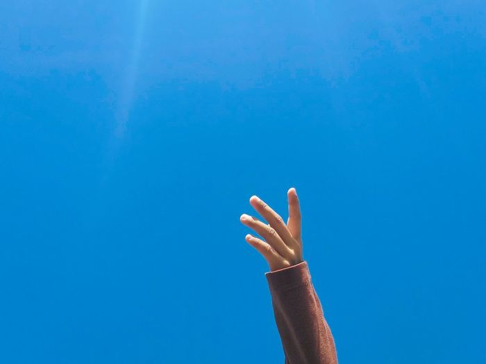 Cropped hand against blue sky