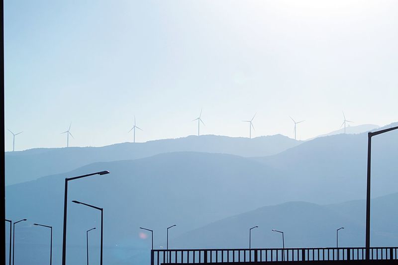 Wind turbines on mountain against sky