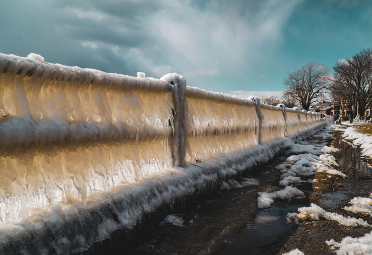 Frozen fence against sky