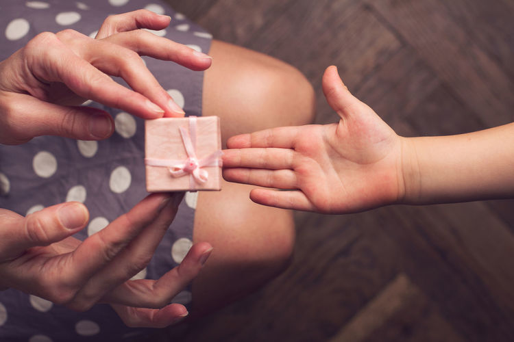 Cropped image of woman giving gift box to child