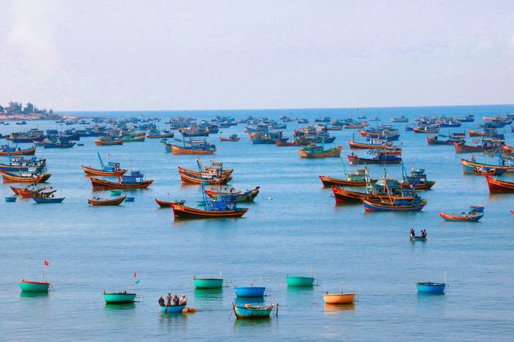Fishing boats anchored on river against clear sky