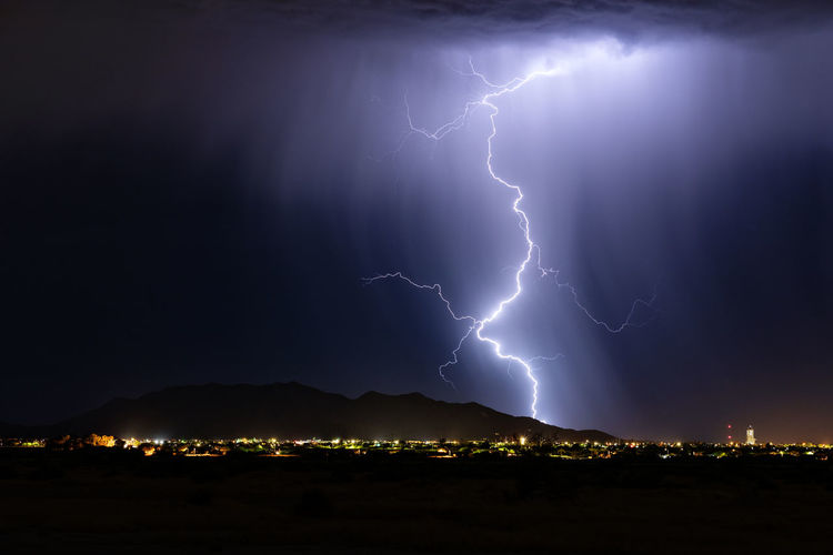 Lightning over illuminated cityscape at night