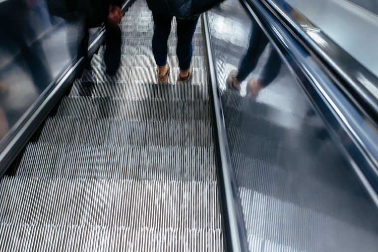 Low section of people standing on escalator
