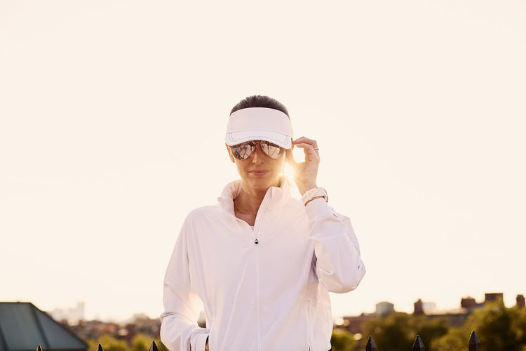A backlit portrait of a woman in white athletic clothing.