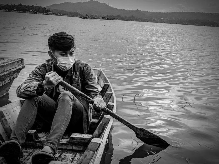 Young man sitting on boat in lake