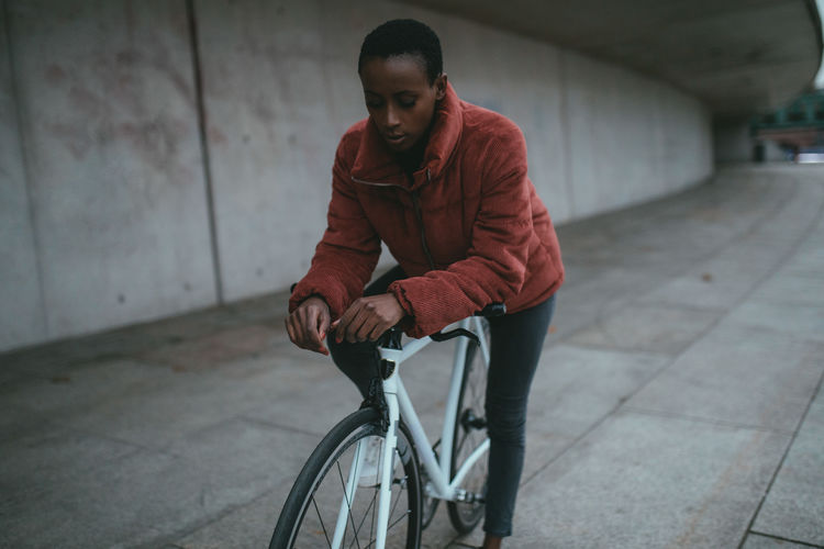 Woman with bicycle on road in city
