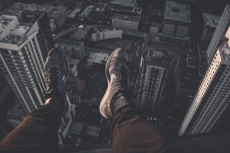 Low section of man sitting on building terrace over cityscape
