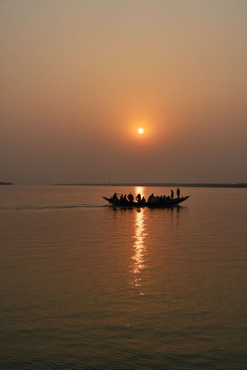 Silhouette boat in sea against sky during sunset