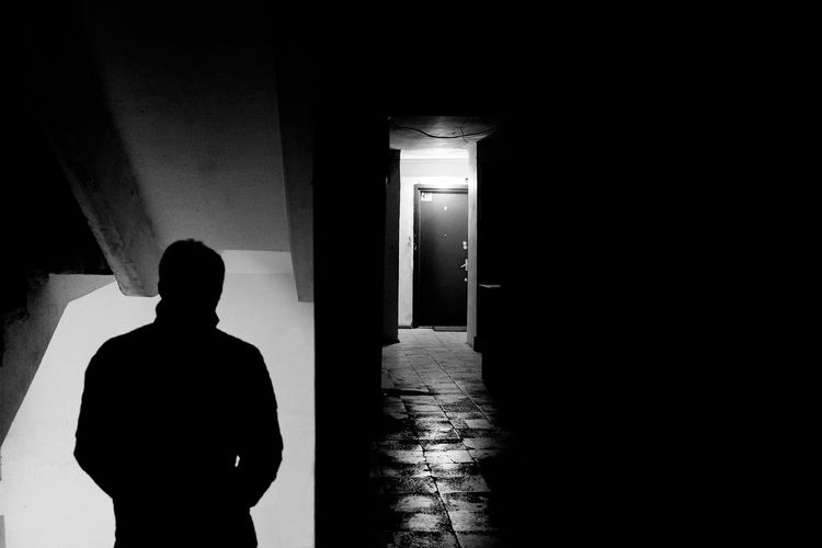 Rear view of silhouette man standing in illuminated corridor