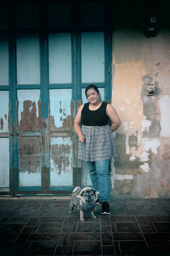 Full length portrait of woman standing against building