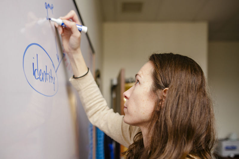 Close-up of a woman researcher drawing a graph on an office whiteboard