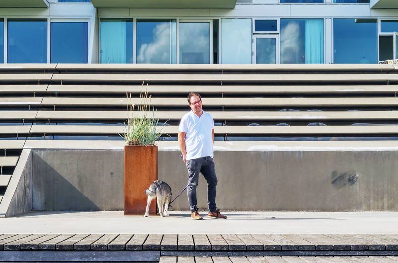 Man with dog standing in front of building