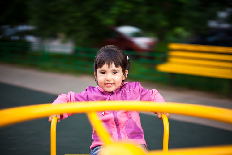Portrait of cute girl playing on outdoor play equipment in playground