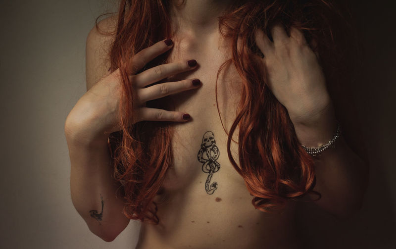 Midsection of woman with hand on hair and tatoos 