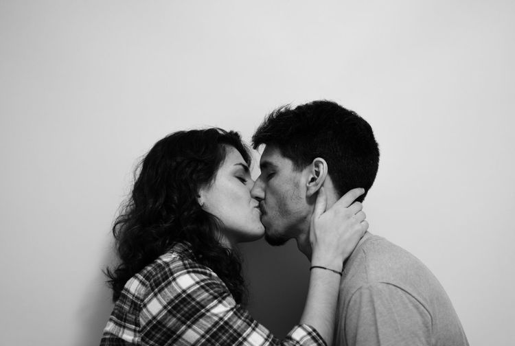 Side view of couple kissing against white background