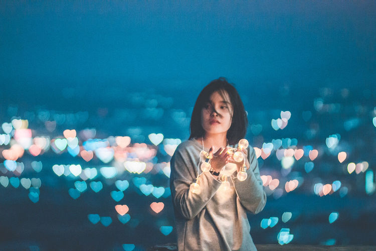 Young woman with illuminated light bulbs at night