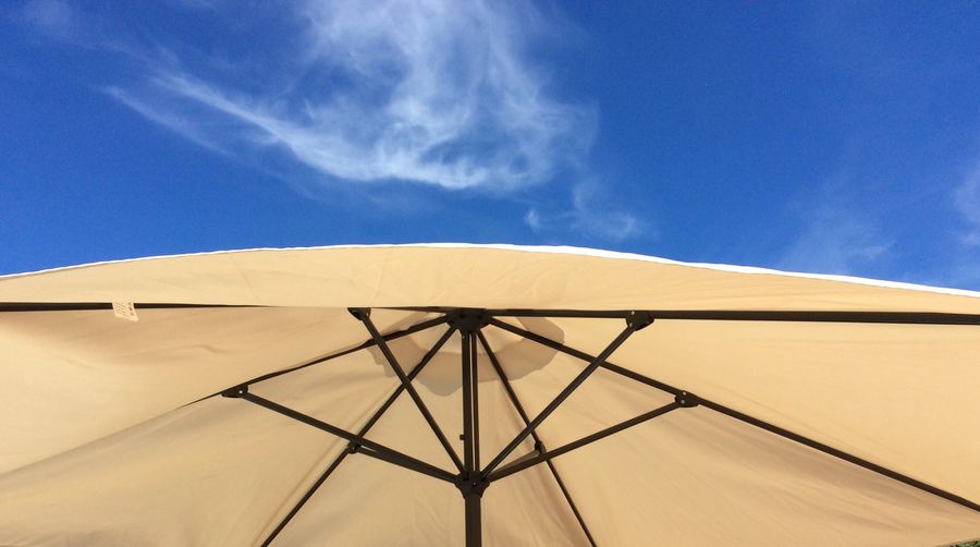 Low angle view of sun umbrella against blue sky