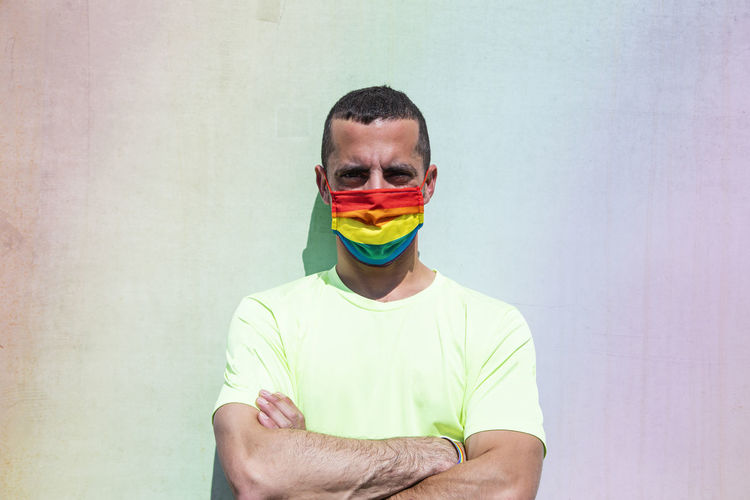 Young man with protective mask and rainbow flag armband. lgtb.