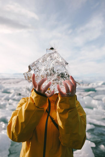Close-up of young woman holding ice against sea