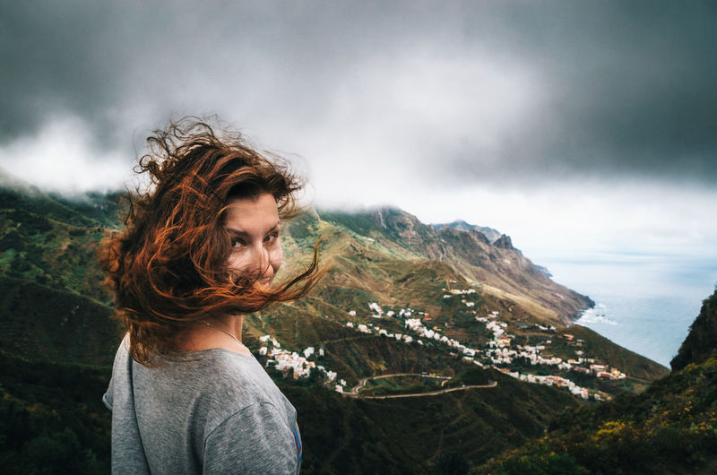Joyful young woman with flying hair hidden her face looks at the camera in front of Taganana village on north of Tenerife. Traveler are enjoying the landscape, Canary Islands, Spain Canary Islands Beauty In Nature Casual Clothing Cloud - Sky Landscape Leisure Activity Mountain Mountain Range Nature One Person Outdoors Real People Scenics Standing Tenerife Village View Young Adult The Week On EyeEm Lost In The Landscape Go Higher Moments Of Happiness International Women's Day 2019