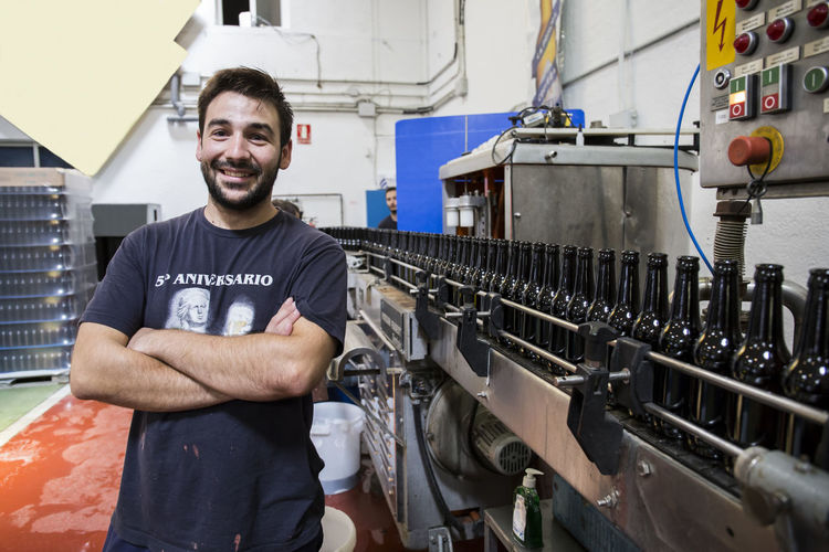 Man standing next to conveyor belt in bottling plant