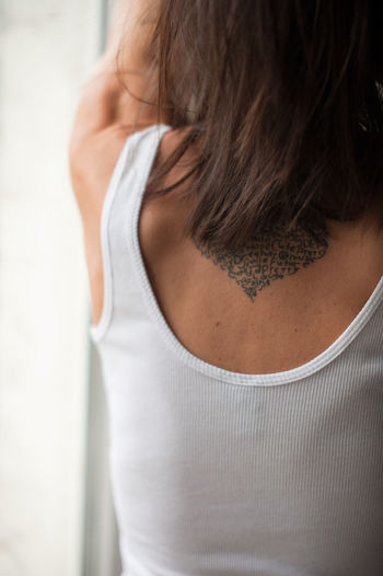 Rear view of woman with tattoo standing at home