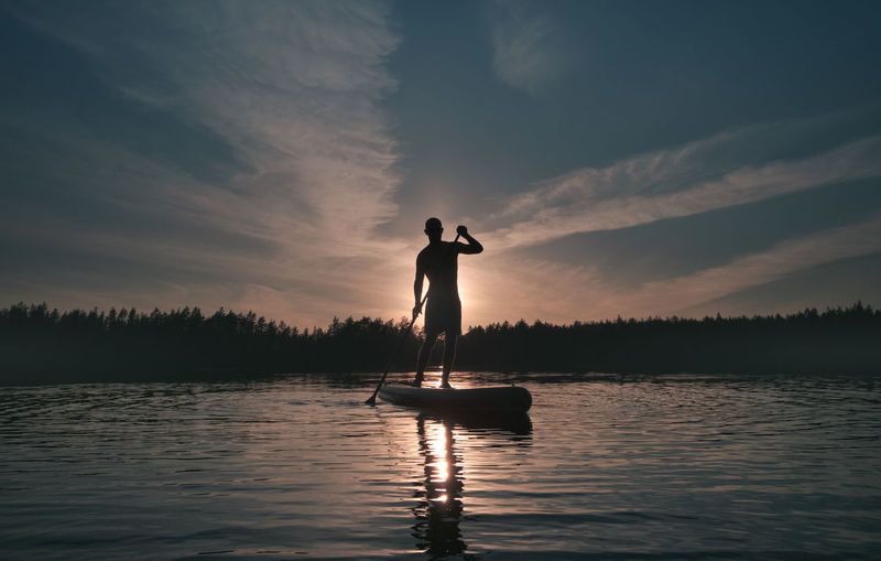 Silhouette of a man with a paddle on a sup surfboard. theme of an active lifestyle