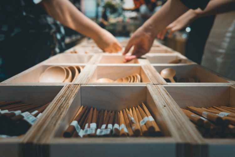 Midsection of people holding wooden spoon in container