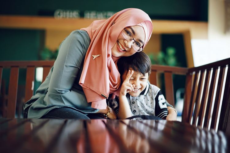 Portrait of mother smiling while sitting with son at table