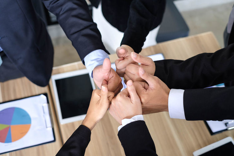 High angle view of colleagues gesturing thumbs up sign over desk