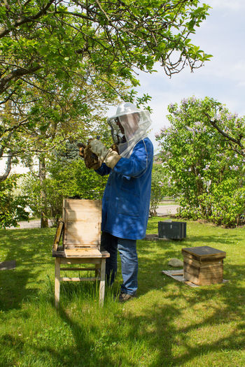 Side view of beekeeper working on grassy field