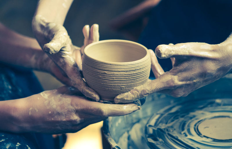 A raw clay pot in the hands of a potter. workshop in the pottery workshop