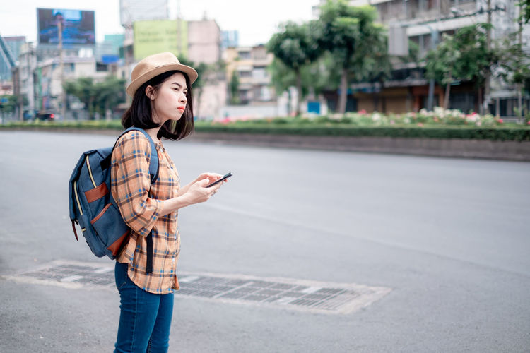 Young woman using mobile phone while standing on street