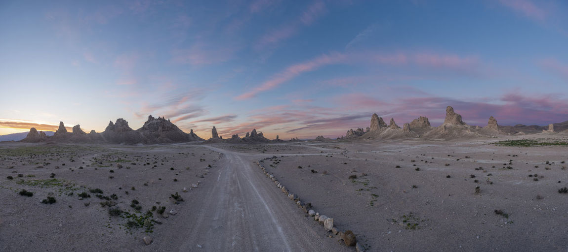 Panoramic view of dirt road against sky during sunset
