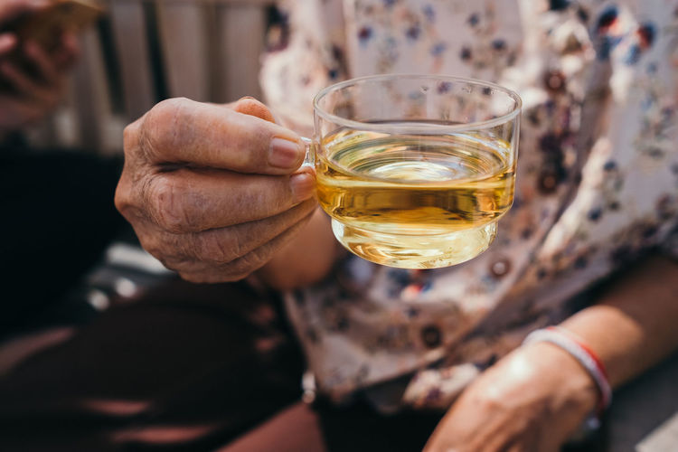 Midsection of senior women holding tea glass